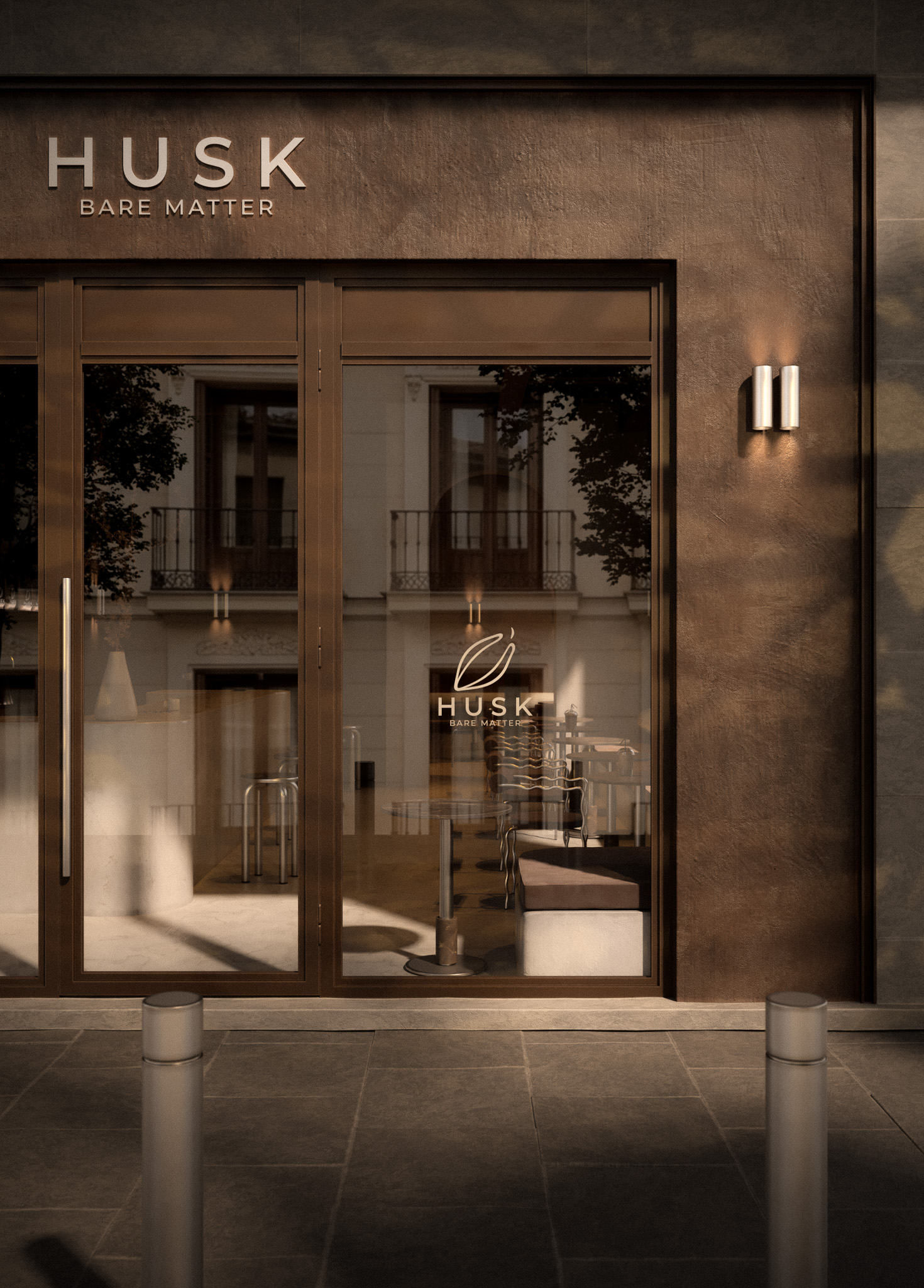 Fachada de la cafetería Husk con rótulo en relieve “Husk Bare Matter”, carpintería metálica oscura y vinilo con el logotipo en el cristal